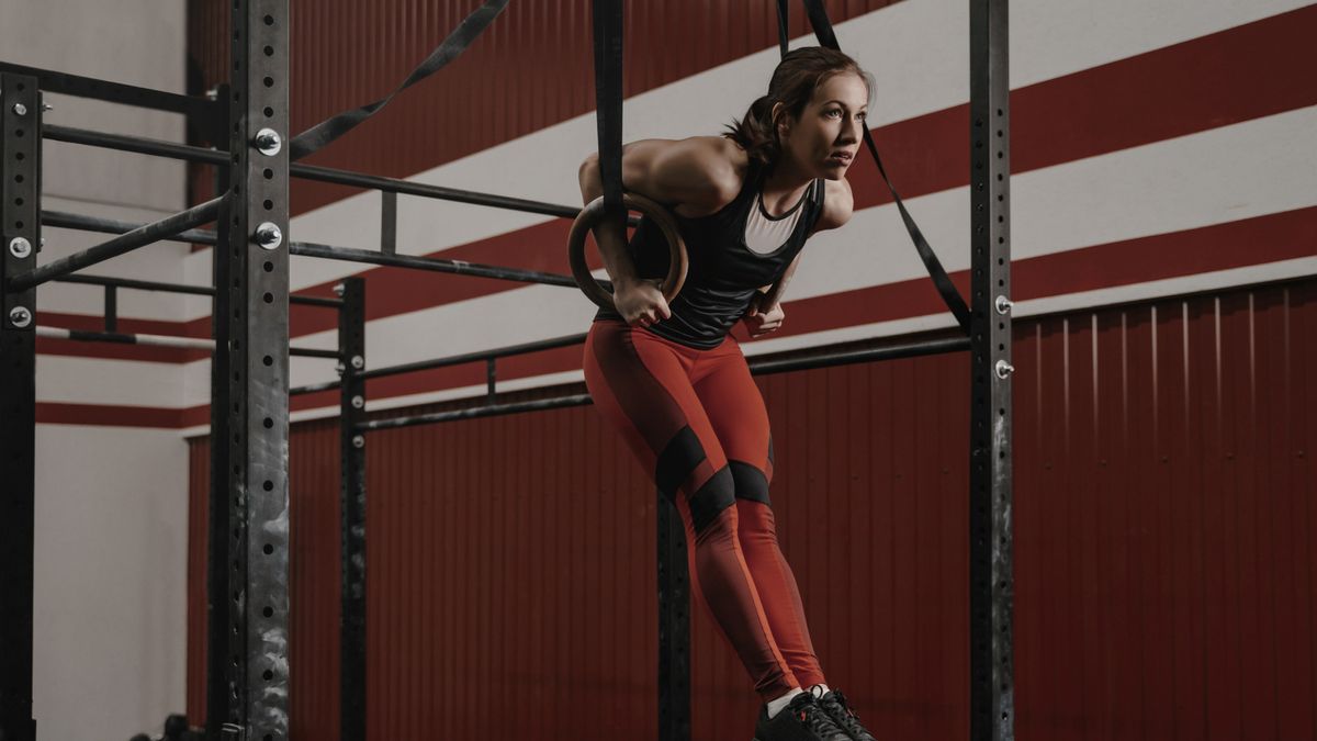 A woman performing a ring muscle-up in a CrossFit gym