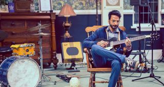Amit Dattani plays guitar in a rehearsal studio setup, playing through a small Supro Delta King combo