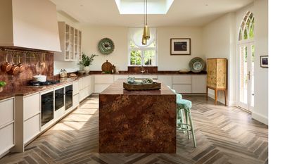 brass and cream kitchen with kitchen island and herringbone flooring