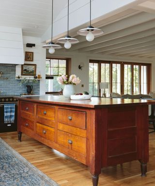 Wood kitchen island with drawers, pendant lights and white panelled ceiling