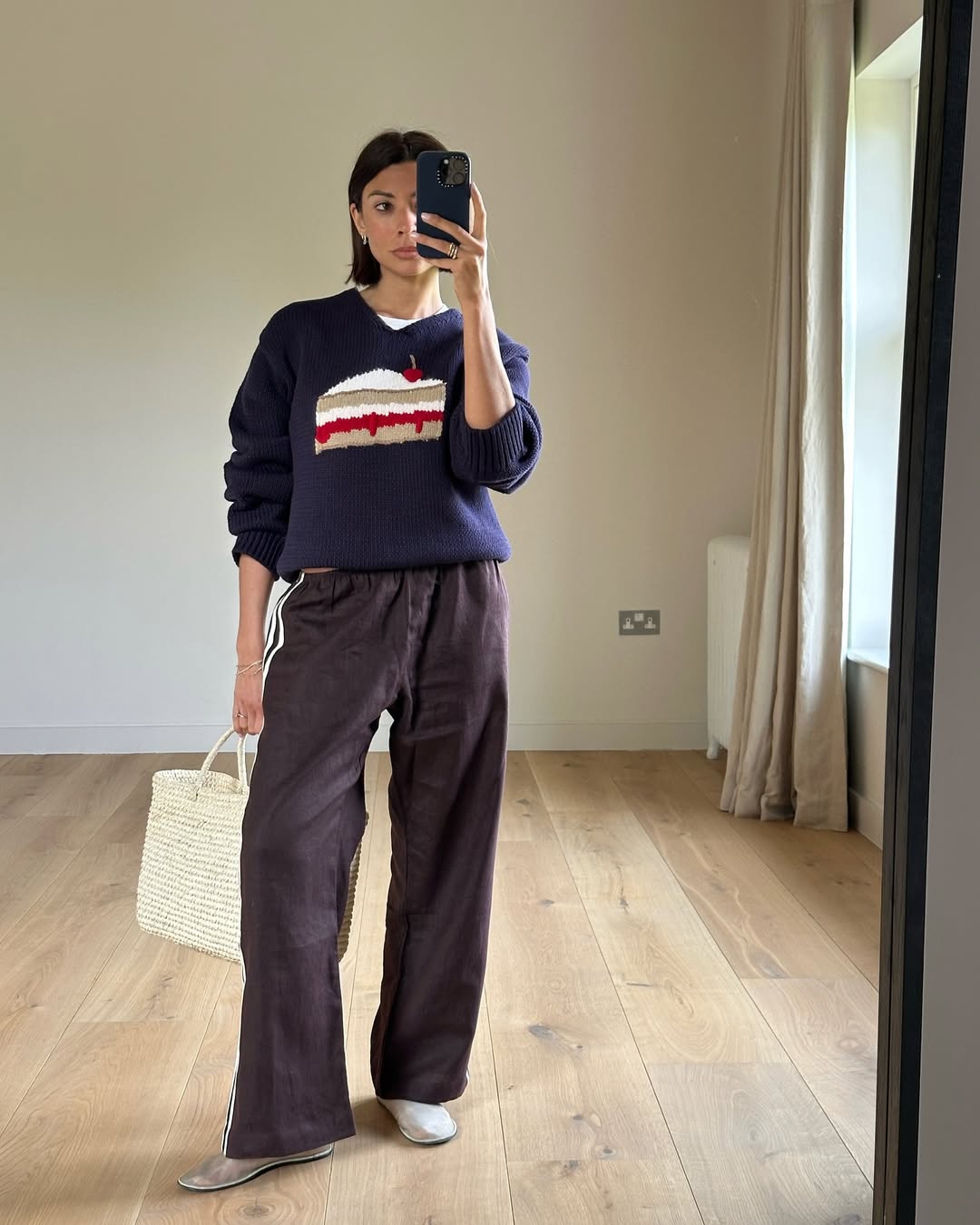 influencer @smythsisters wears a graphic sweater with striped linen track pants and white mesh ballet flats