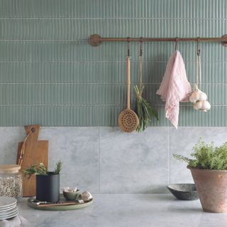 Kitchen with light green tiles and hanging utsensils