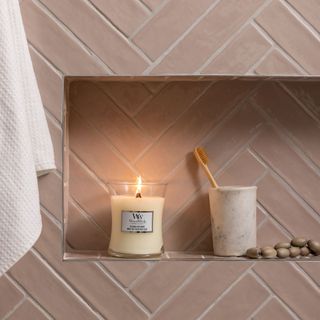 WoodWick coconut scented candle in bathroom with pink herringbone wall tiles