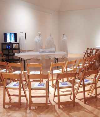 Wooden chairs around table and mannequins covered in white material