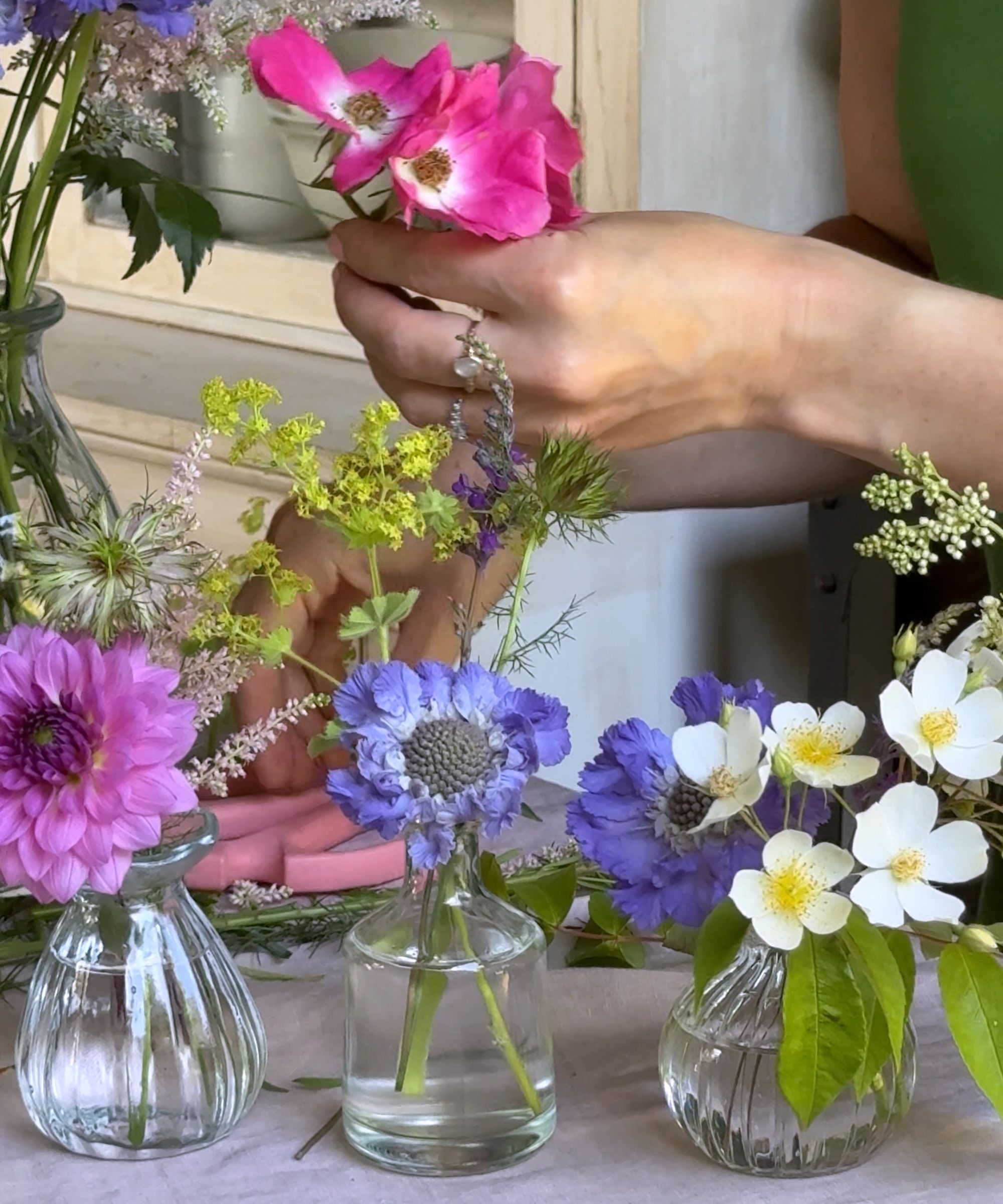 Arranging pink, purple and white flowers in bud vases