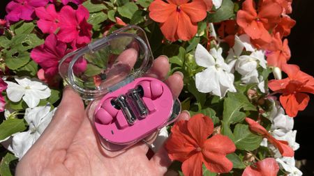 Nothing Ear (3a) on a floral background, with pink, red and yellow flowers 