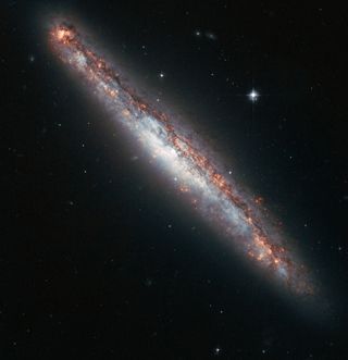 This NASA/ESA Hubble Space Telescope image shows the edge-on profile of the slender spiral galaxy NGC 5775, which is surrounded by a halo of gas that astronomers suspect is kicked up by star explosions like a galaxy-size fountain.