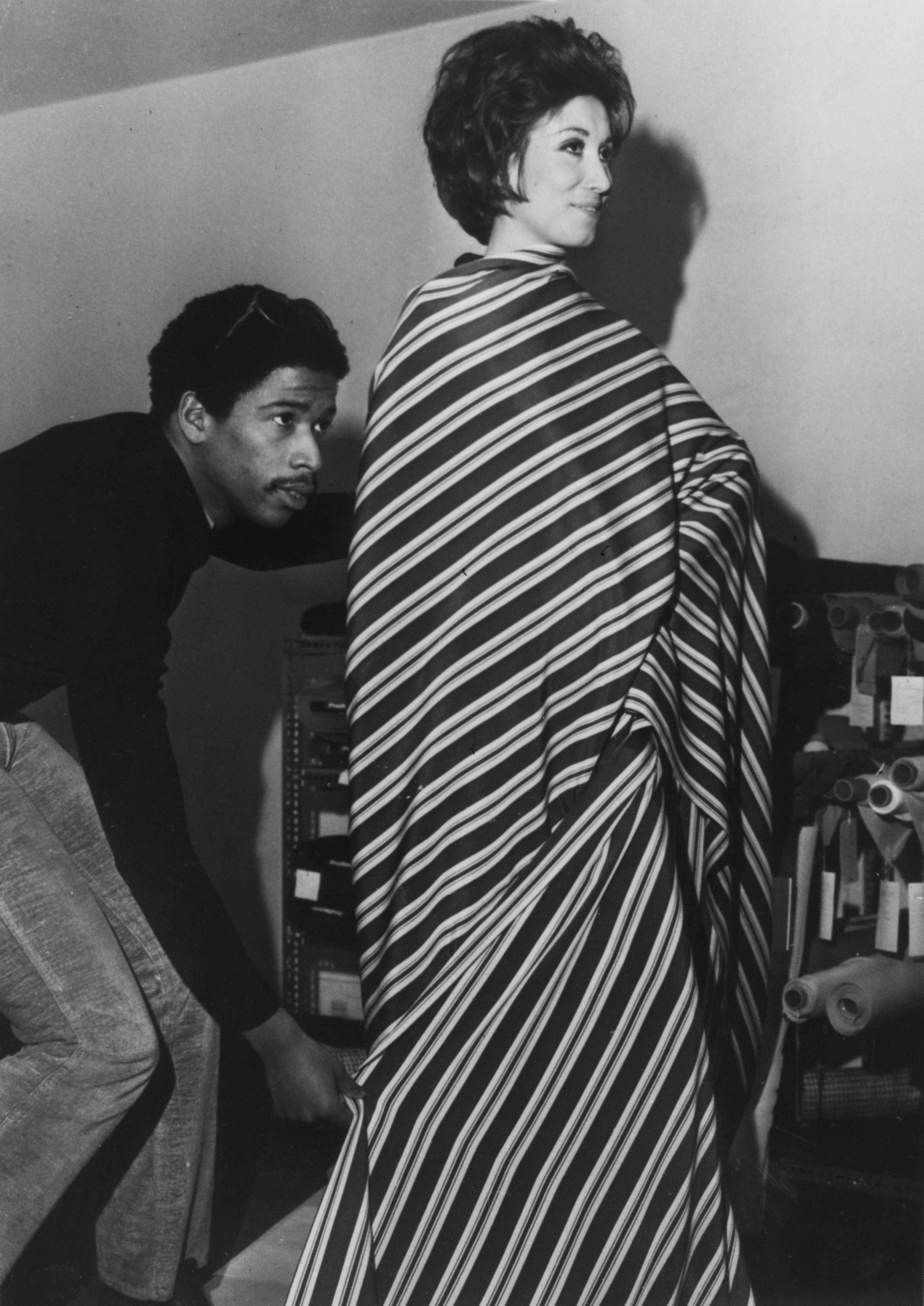 Jay Jaxon prepares a model in a draped striped dress