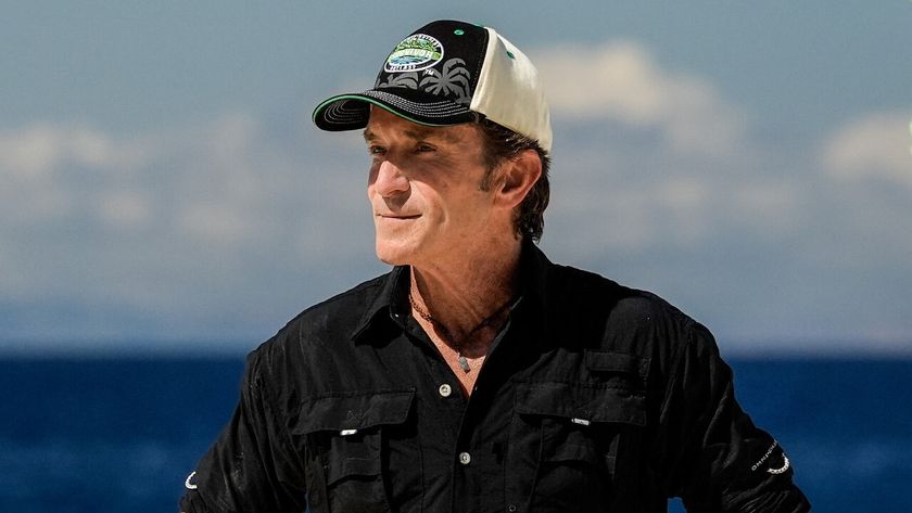 During the Survivor Season 48 premiere, Jeff Probst, wearing his trademark shirt, hat, and necklace, observes the contestants. 