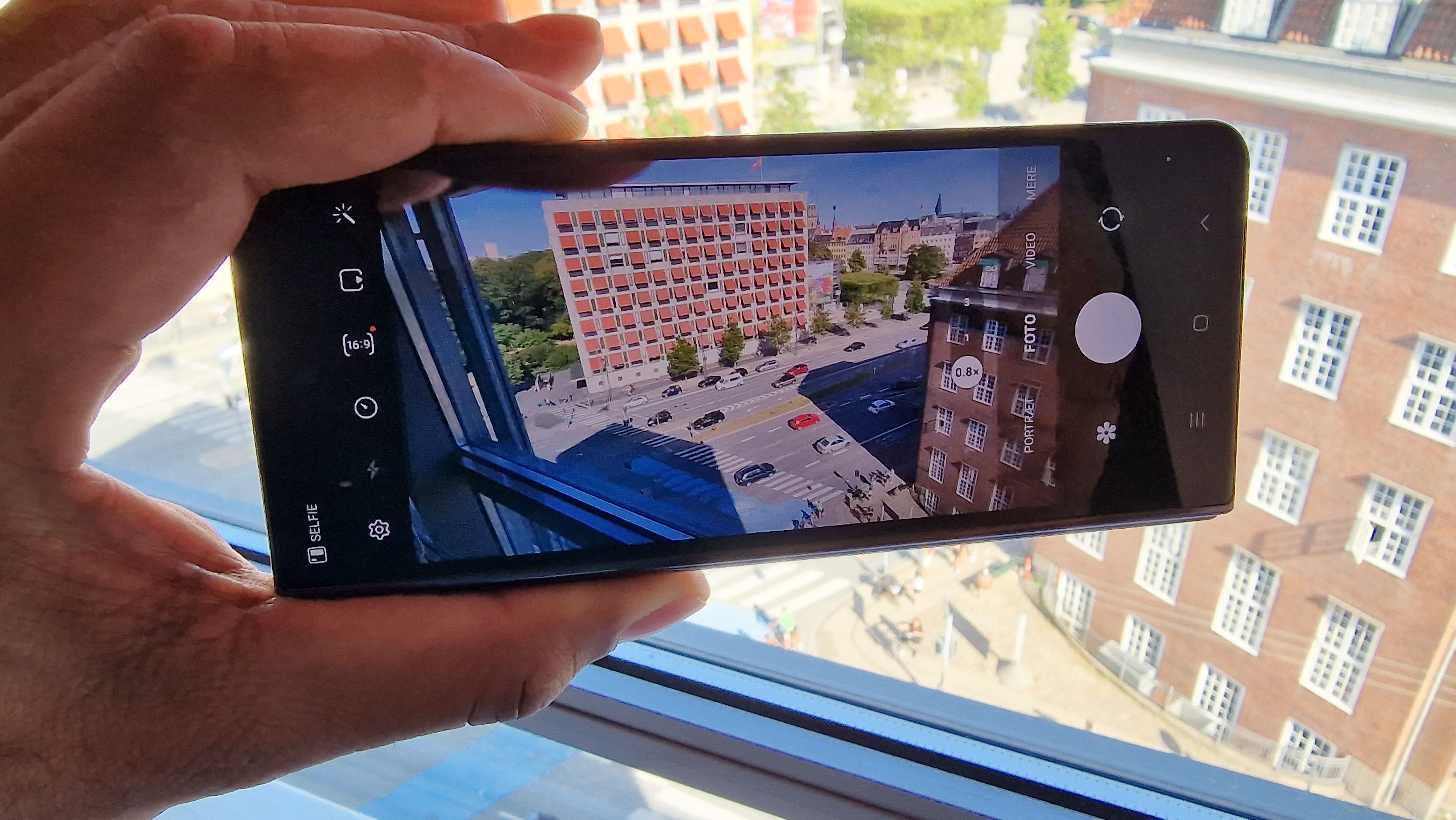 Samsung Galaxy Z Fold 4 holdt i hånden sammenklappet med kamera-app'en kørende på frontskærmen.