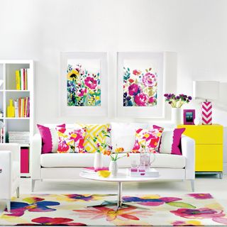white living room with colourful floral rug cushions and artwork, with a contemporary white couch set