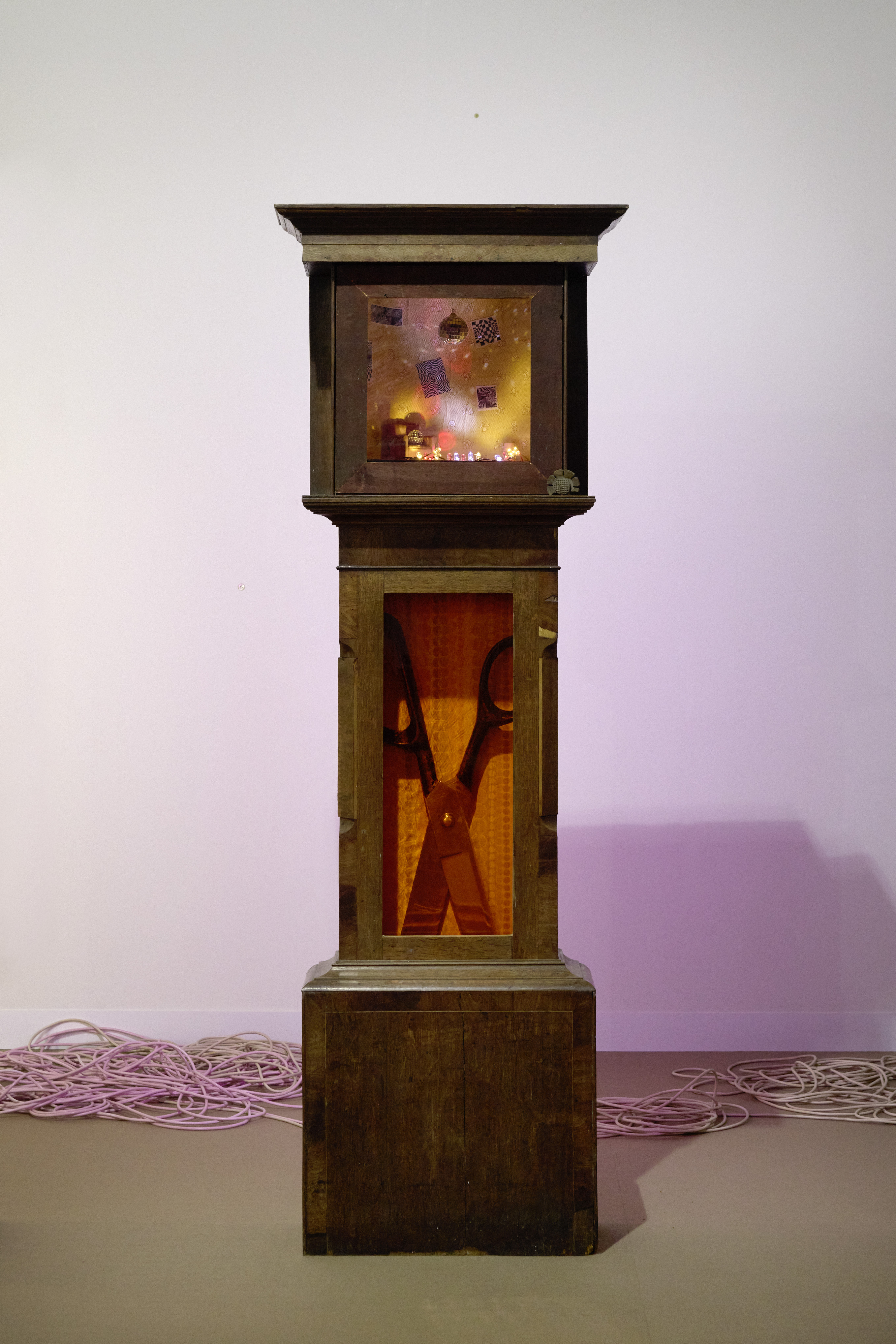 Installation views of a series of grandfather clocks displayed in an art gallery.
