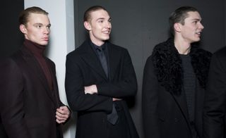 Three male models laughing stood in black jackets