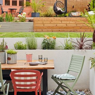 garden table and chairs on lower level, grass and decking with furniture on higher level