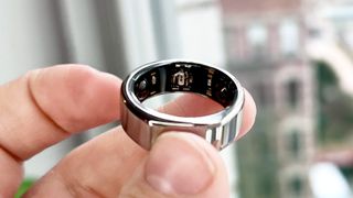 Oura Ring Gen 3 smart ring between a person's fingers