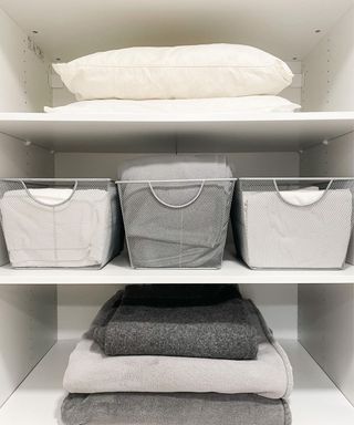 Bathroom towels stored in see-through bins on a shelf