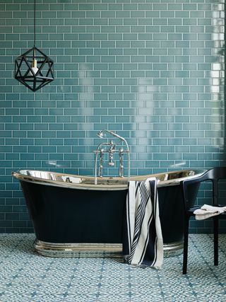 Patterned tiles in a turquoise bathroom with free standing bath