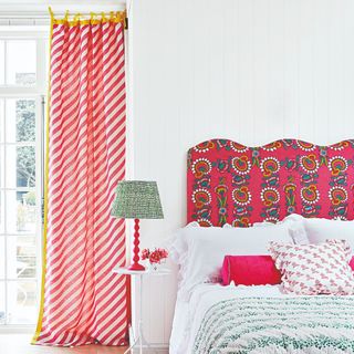 A bedroom with a patterned wavy headboard and striped curtains