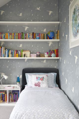 A kid's bedroom with grey and white patterned wallpaper and grey and white patterned bedding