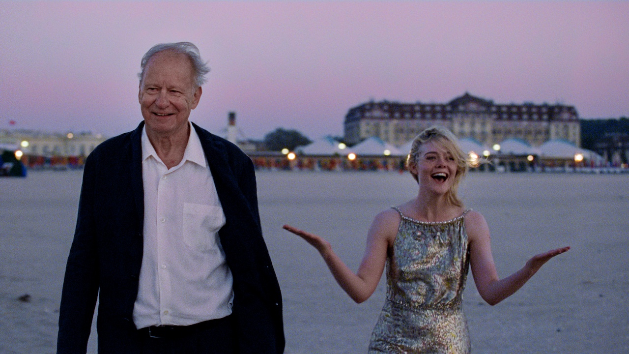 Stellan Skarsgard and Elle Fanning smiling next to each other during a sunrise in Sentimental Value