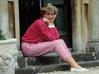 An old photograph on Princess Diana, sitting on a stone step outside an old house.