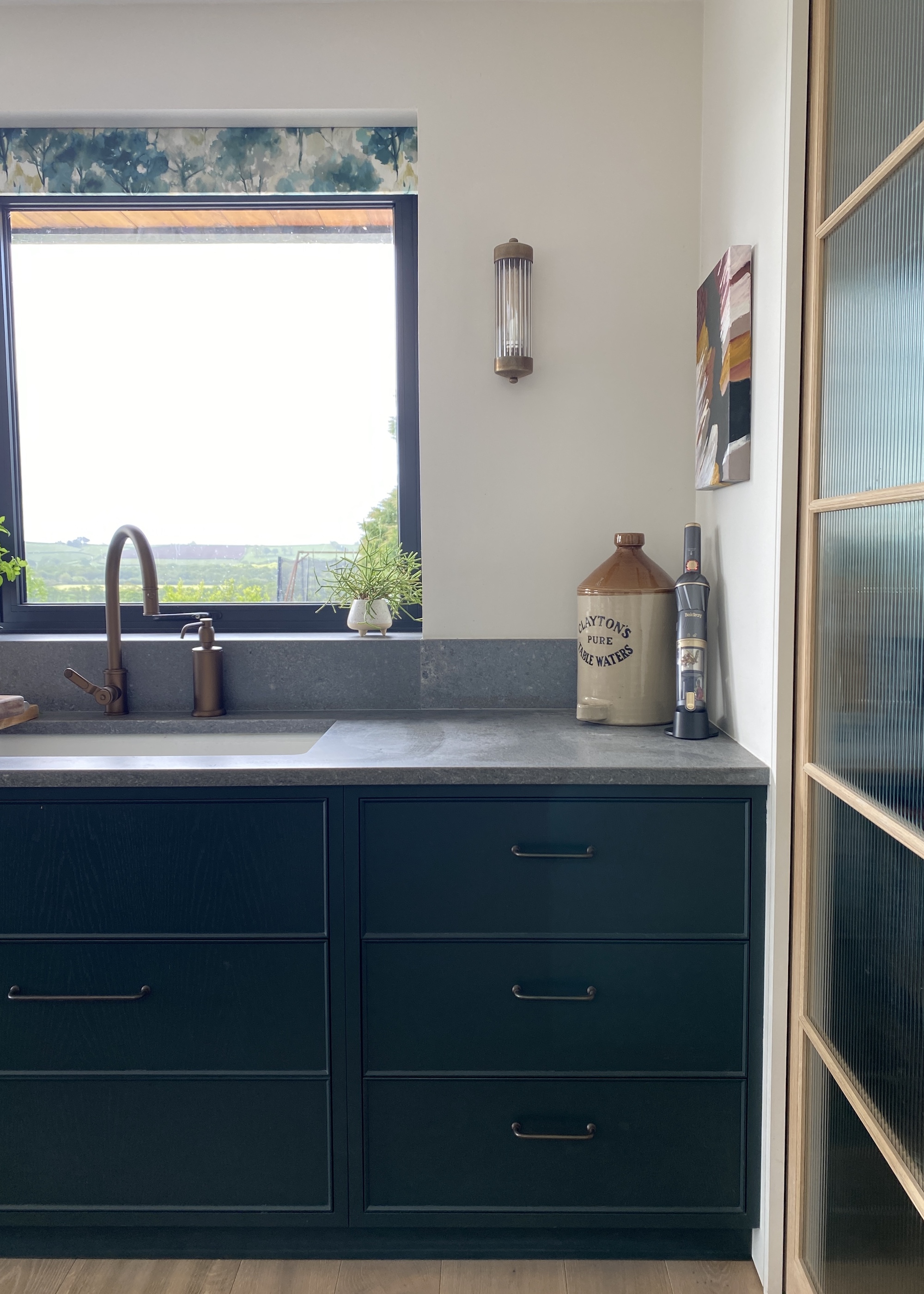 dark green cabinets with grey worktops and white walls