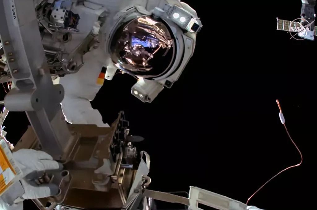 an astronaut sideways in a spacesuit gazing at the camera, during a spacewalk