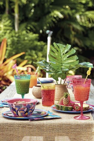 colourful glassware and botanical bowls and plates outside in a garden