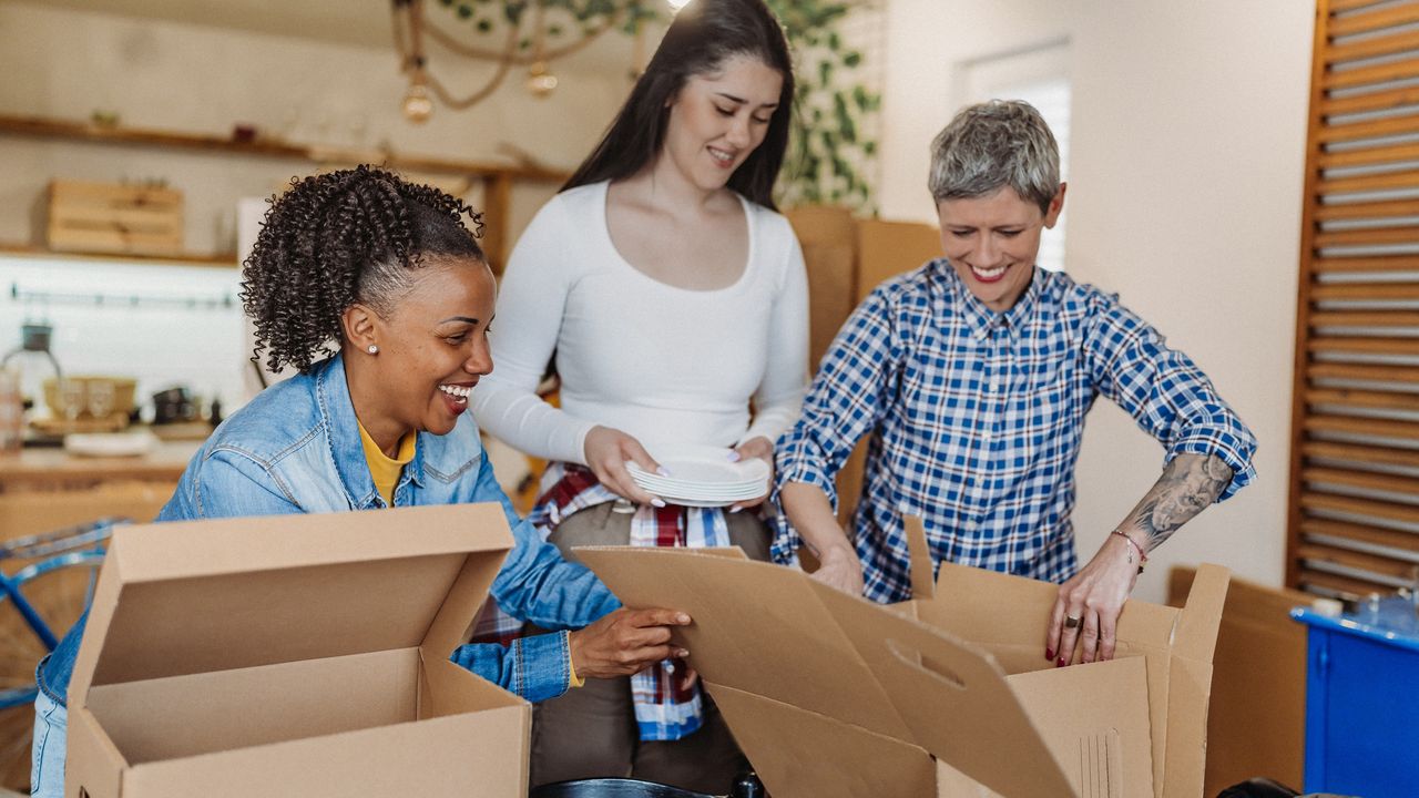 Three women pack boxes in preparation for a move.