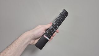 Remote control for the TCL 32S5400 held in someone's hand