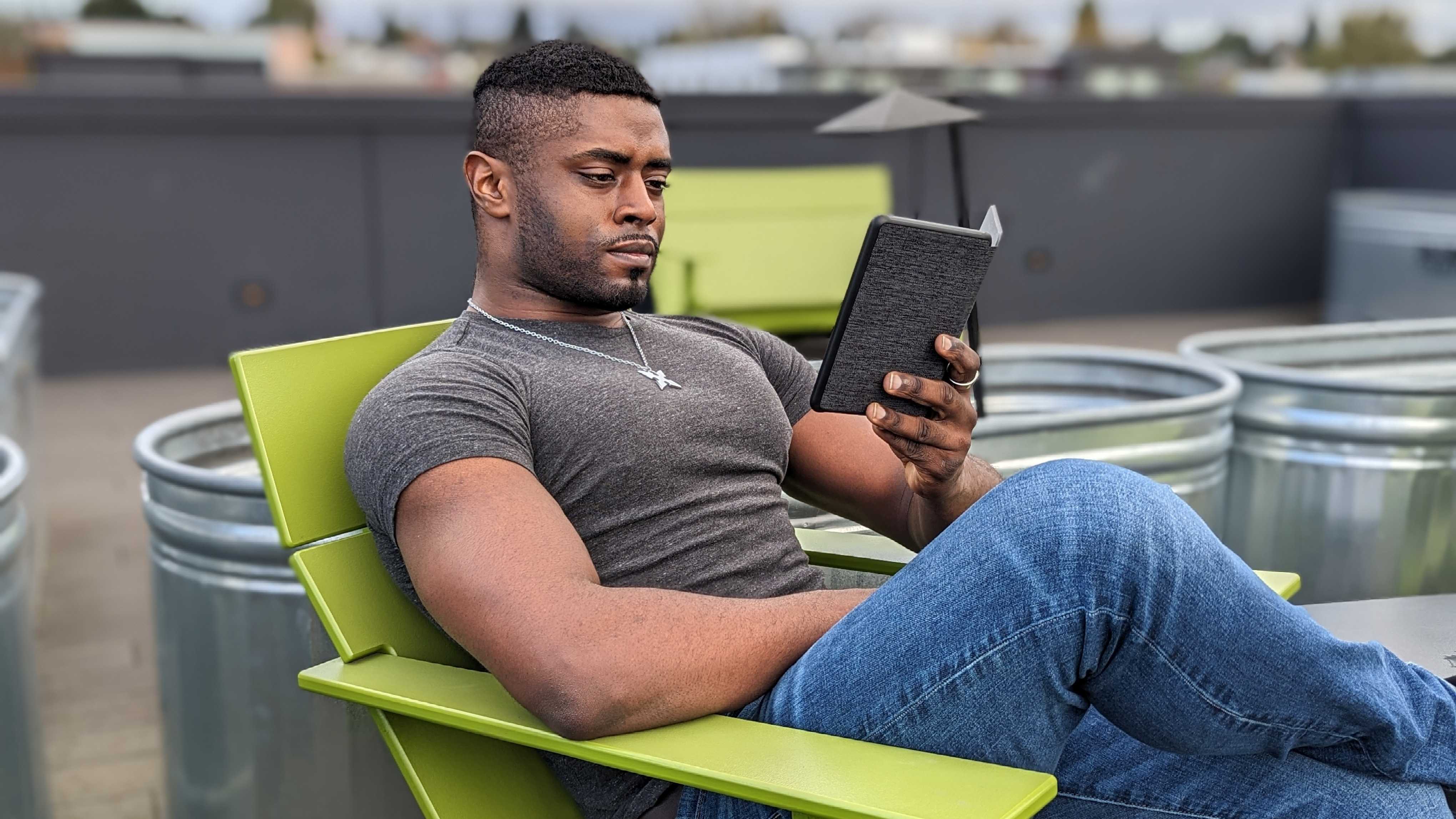 Sentado y sosteniendo el Kindle (2022) afuera