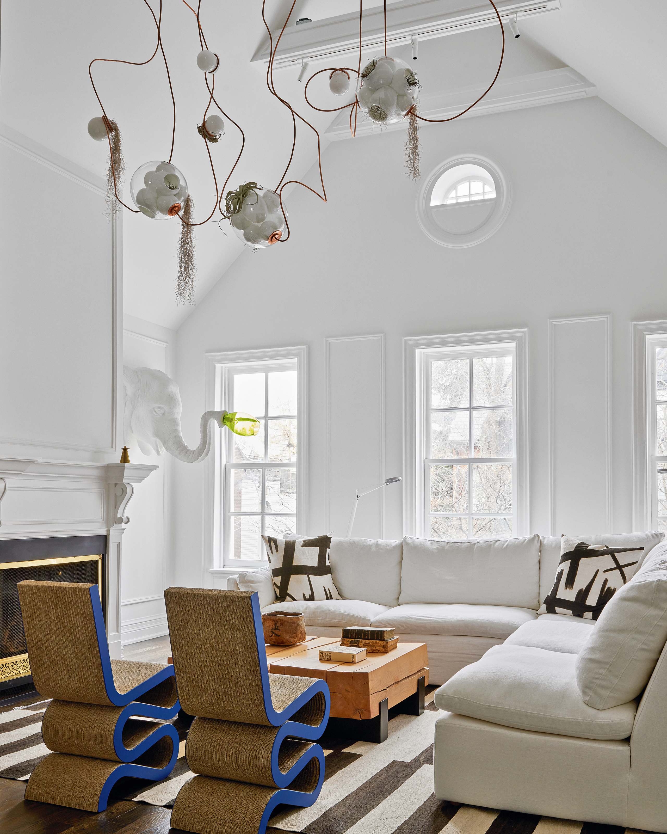 White living room with corner sofa, abstract graphic black and white cushions, wood coffee table and cobalt blue Wiggle side chairs