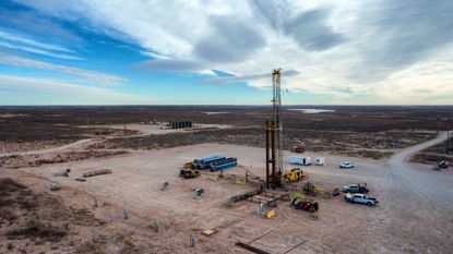 An oil rig sits in the middle of a dirt field