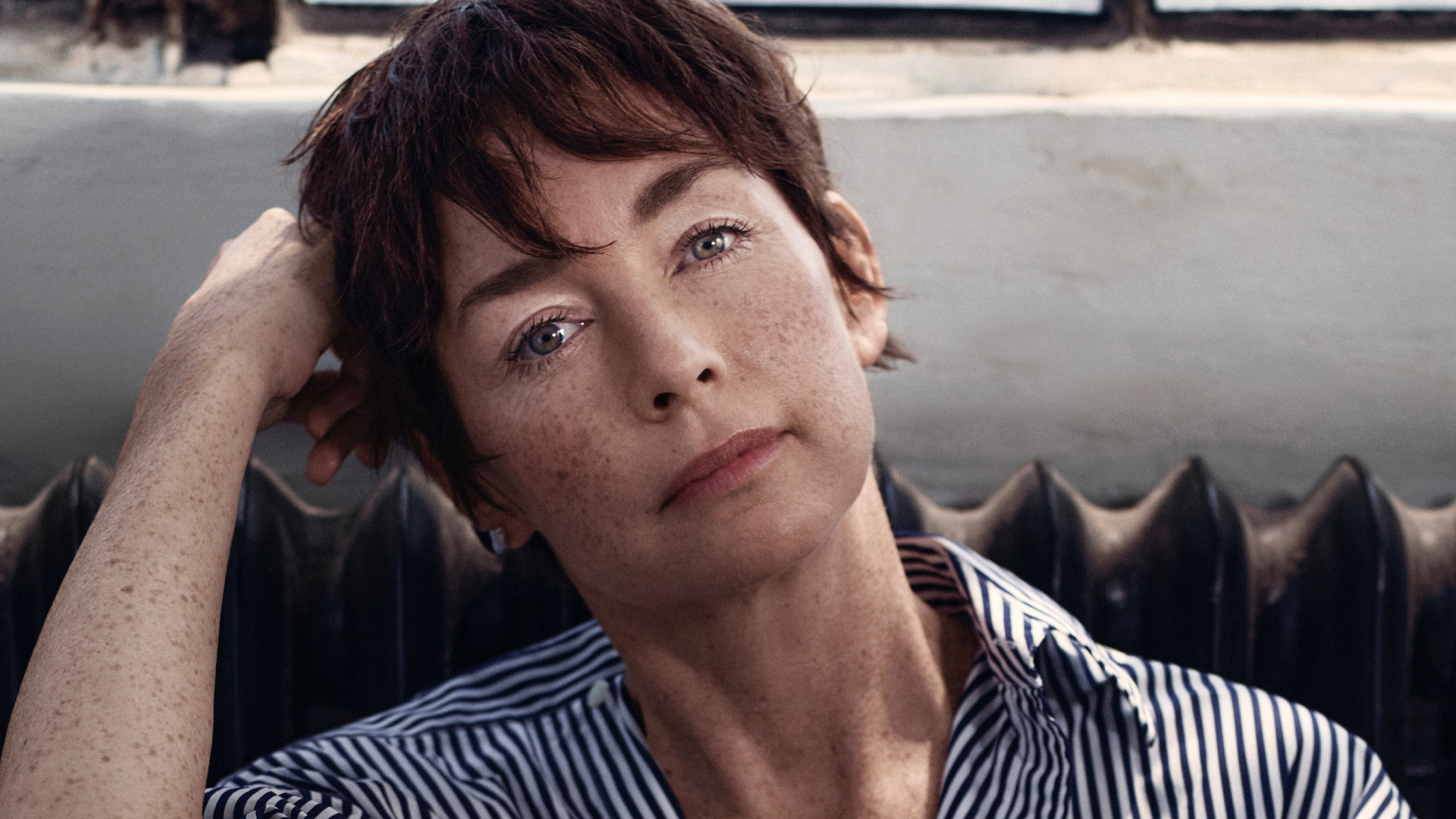 A portrait of actress Julianne Nicholson, sitting in front of a window and a radiator.