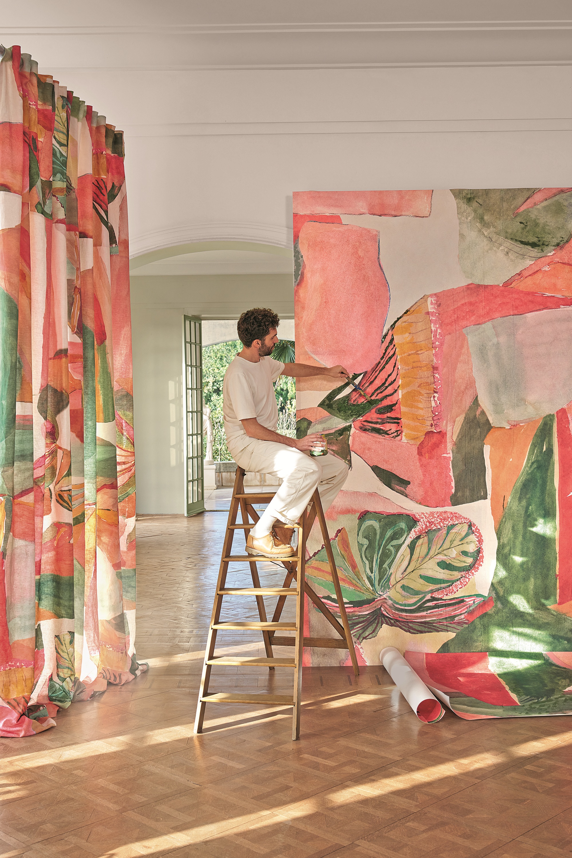a man on a ladder painting wallpaper with curtains in the background