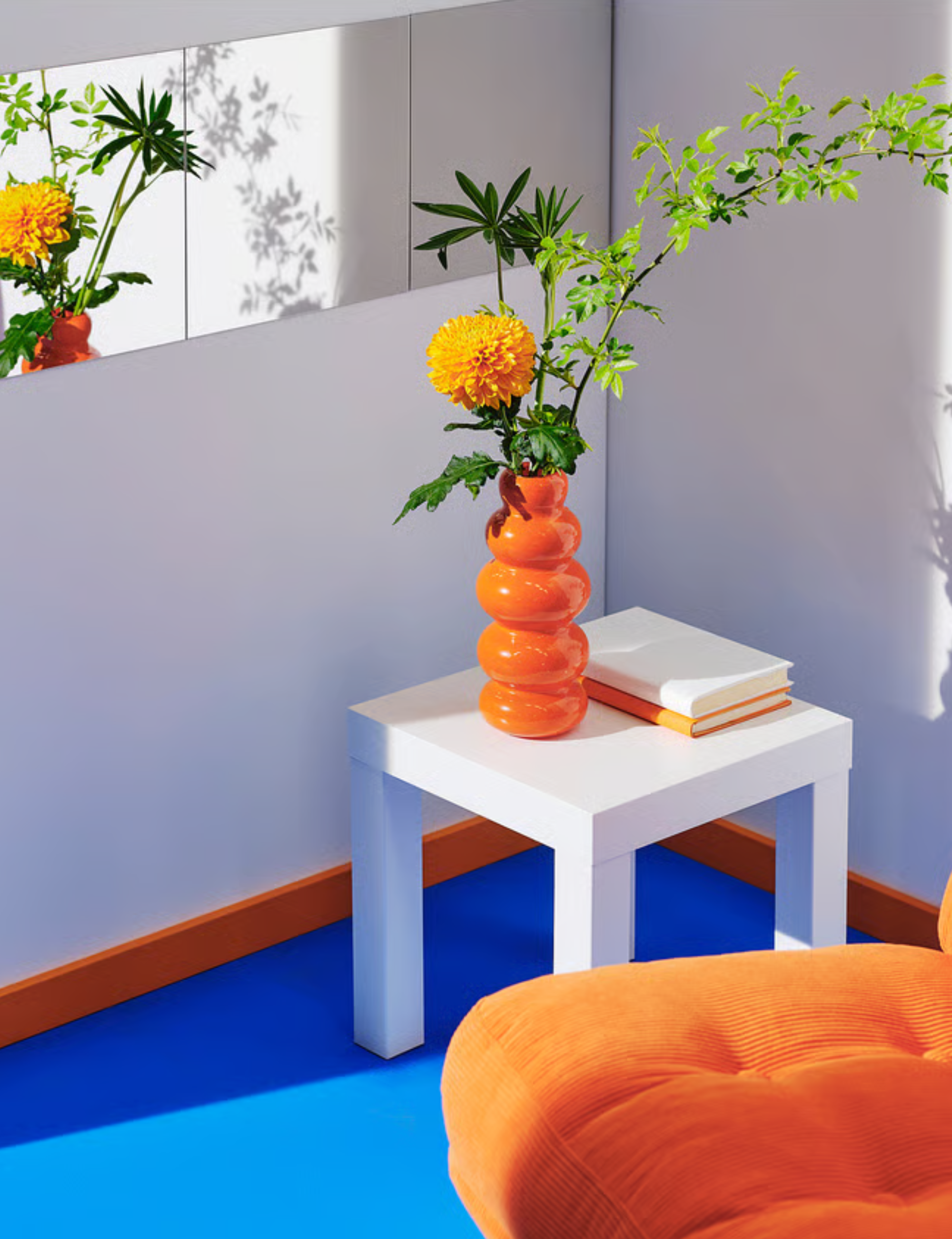 Orange vase and armchair pictured atop of a cobalt blue area rug