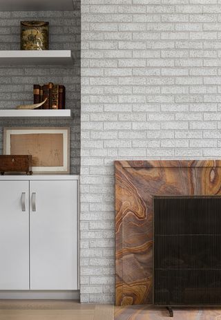 minimalist living room with brown marbled fireplace and grey brick wall