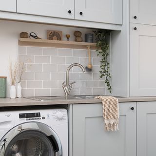 Laundry room with neutral cabinetry, washing machine and metro tiled splashback