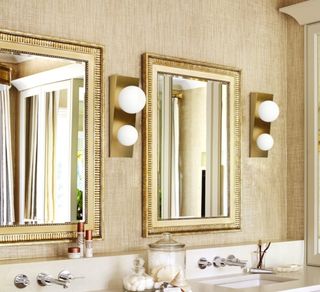 Gold framed bathroom mirrors with LED lighting with gold details above twin basins