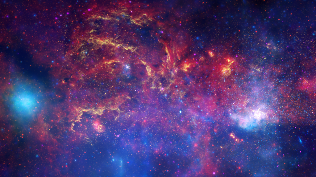 An image of the Milky Way&#039;s galactic center with beautiful purples, blues and some glowing white hues.