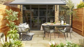 small paved patio with awning and garden furniture