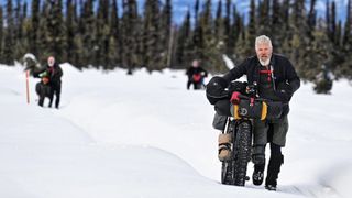 Rider pushing in the snow at the Iditarod mountain bike race