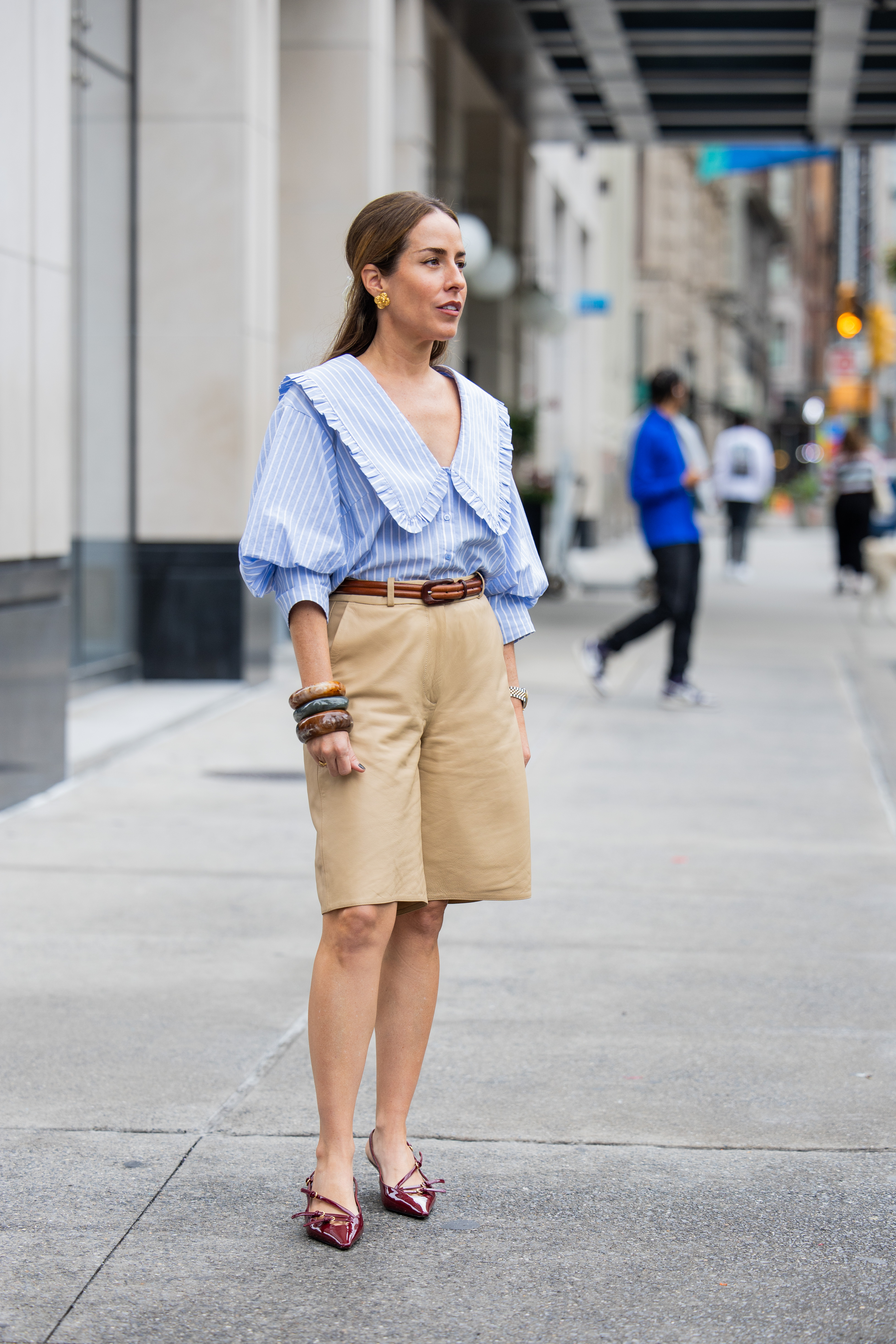 woman wearing blue button-down, beige bermuda shorts, and heels