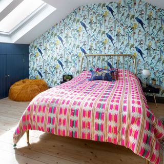 Bedroom with blue bird patterned wallpaper and pink quilt