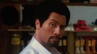 Dwayne Johnson raises his eyebrow while wearing an afro in the comedy Be Cool