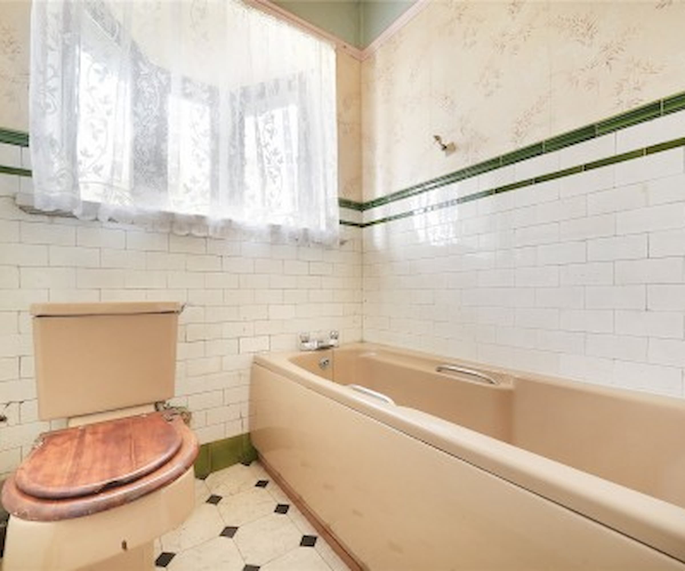 A bathroom with peach bath and toilet
