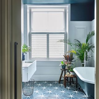 Bathroom with window with window blinds, patterned flooring, bathtub