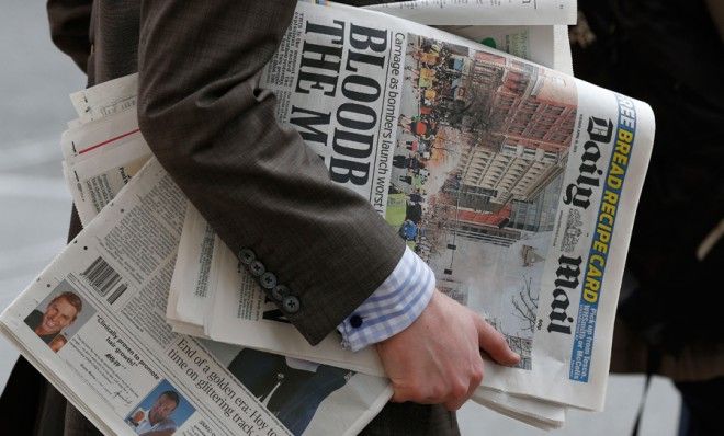 A man carries newspapers featuring frontpage coverage of the Boston Marathon blasts in London on April 16.