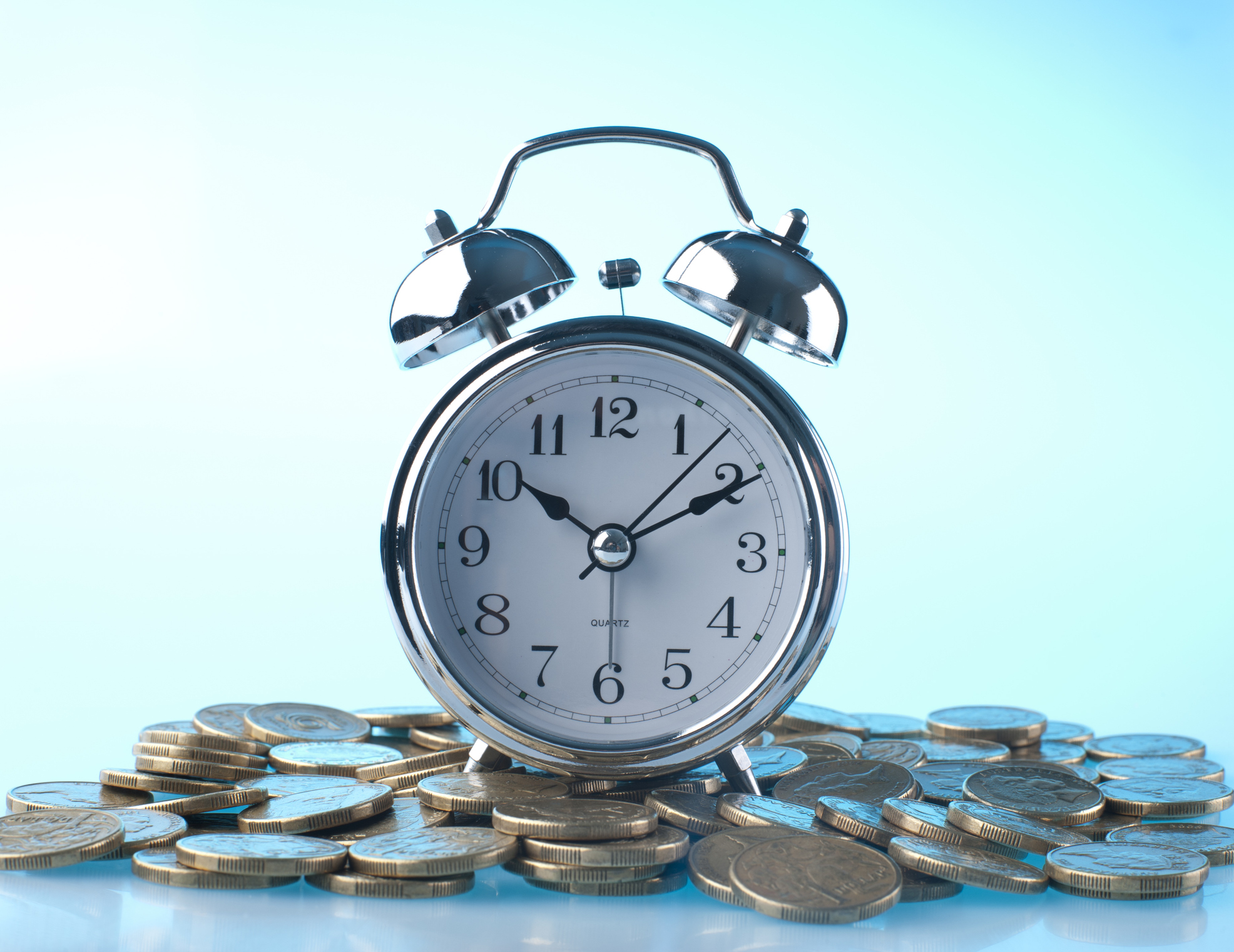 alarm clock on pile of coins