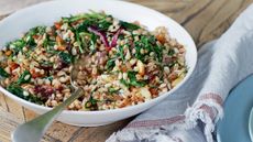 Spelt, almond and arugula salad in a white bowl